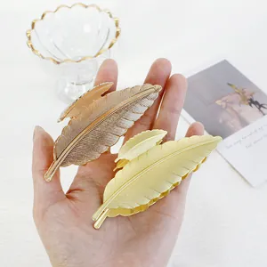 Dettaglio delle mollette per capelli in metallo dorato e oro rosa a forma di piuma