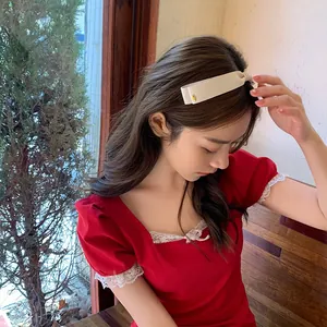 Détail du serre-tête en tissu crème avec double nœud et petite boucle en métal