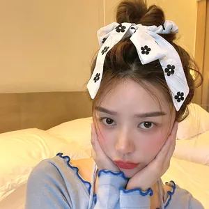Detail showing white floral bow scrunchie with black flower pattern on model's hair