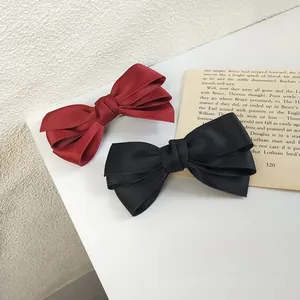 Detail of red and black triple-layered silk bow hair clips with textured ribbon fabric