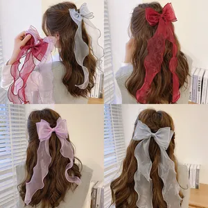 Elegant large organza bow hair clip with long ribbons shown on long wavy hair