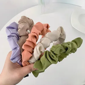 Five assorted colors of pleated fabric headbands showing soft textures and vintage style