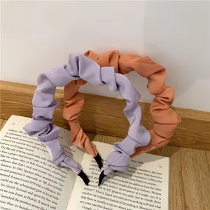 Detailed view of lavender and coral pleated fabric headbands on a vintage book