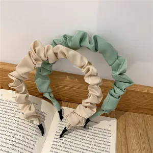 Detail of pleated fabric headbands in beige and sage green on a vintage book
