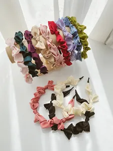 Detail of colorful pleated satin bow headbands on a cream jewelry stand with soft lighting