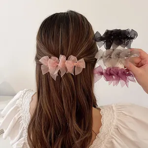 Close-up of four layered mesh bow hair clips in pink, black, grey and purple colors