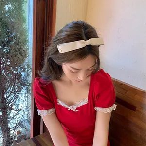 Serre-tête noeud en ruban côtelé crème avec détail doré porté par un mannequin