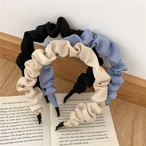 Detailed view of pleated fabric headbands in black, blue, and beige on a vintage book