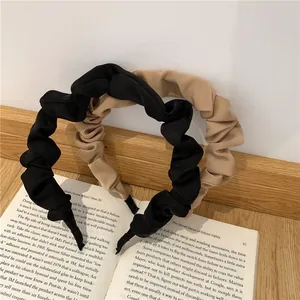 Detail view of pleated fabric scrunchie headbands in classic black and beige on an open book