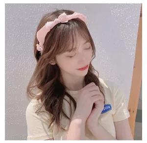 Detailed view of a soft pink satin bow headband worn by a model in outdoor lighting