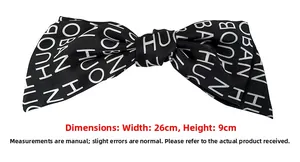 Detail of a large 26cm black satin bow hair clip with white letter print design