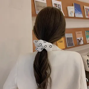 Detail van witte stoffen haarelastiek met zwarte lachende gezichtjes op het haar