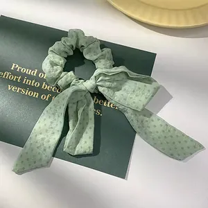 Detailopname van een lichtgroene scrunchie met stippen en strik op een kaart