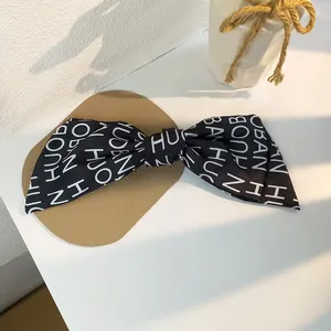 French vintage oversized black bow hair clip with white letter print on a leather pad
