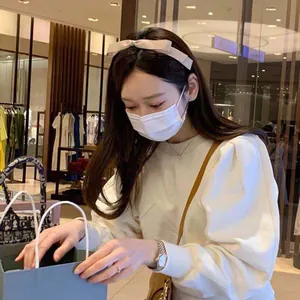 Serre-tête élégant à nœud beige en satin brillant porté par un mannequin de style doux