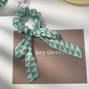 Detail of green and yellow geometric pattern scrunchie with long ribbon streamers