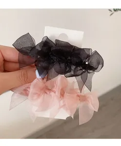 Detail showing two organza bow hair clips in black and pink on a retail card