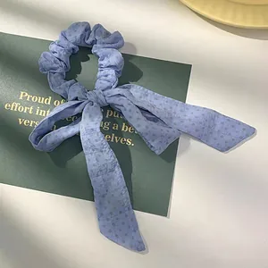 Detailopname van blauwe scrunchie met stippen, strik en lange soepele linten