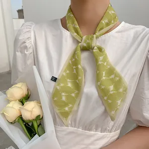 Light green mesh silk hair scarf with white leaf print worn with a white blouse