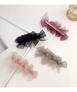 Detail of four colorful layered lace bow hair clips with gold metal clips on a white tray