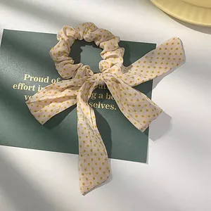 Detailopname van beige haarelastiek met gele stippen en strik op een groene kaart