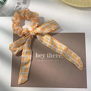 Detail of yellow plaid scrunchie with long ribbons and soft fabric texture
