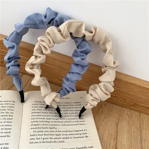 Detail of pleated fabric headbands in morandi blue and creamy white on a book