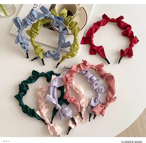 Detail view of seven colorful pleated satin bow headbands in various summer shades