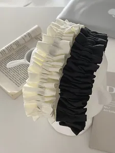 Close-up of elegant pleated wide headbands in cream and black fabric on a model
