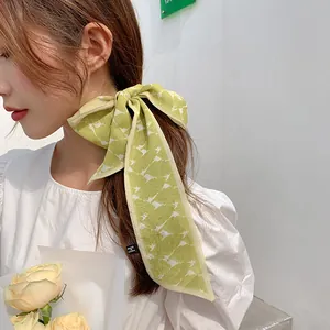 Detail of light green floral chiffon scarf tied as a bow hair tie on a low ponytail