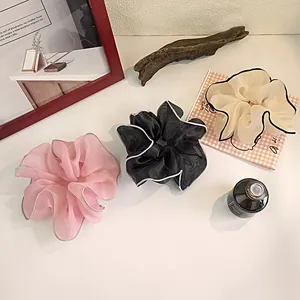 Detail of large mesh hair scrunchies in pink black and beige with wavy contrast edges