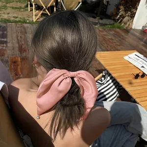 Détail d'un nœud papillon en satin rose avec breloques de perles sur fond de bois