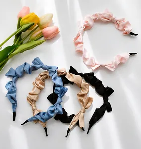 Detail of satin pleated headbands with bows in pink, blue, champagne, and black colors