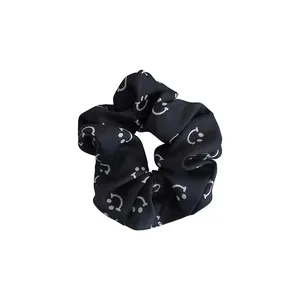 Black scrunchie with white smiley face pattern made of smooth satin fabric for women