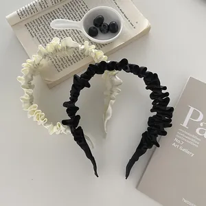 Detail of pleated fabric headbands in black and cream beige with wavy texture