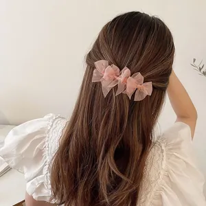 Elegant pink mesh bow hair clips styled on long brown hair for a French vintage look