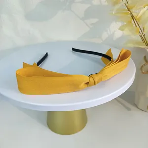 Détail d'un serre-tête à nœud jaune avec texture de tissu à chevrons sur un présentoir