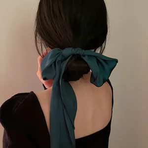 Vue détaillée d'un long ruban en satin vert foncé noué élégamment dans un chignon