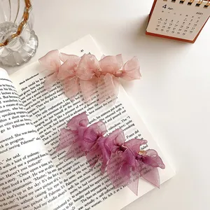 Elegant layered lace bow hair clips in pink and purple mesh on vintage book