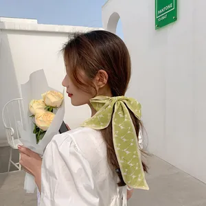 Detail of light green floral mesh hair scarf ribbon tied in a bow on a female model