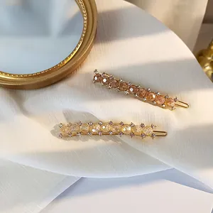 Elegant gold metal hair clips with amber and champagne crystals on white silk fabric