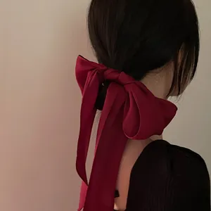 Élégant nœud à cheveux en satin rouge foncé avec de longs rubans sur cheveux bruns