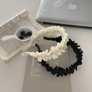 Detail of pleated fabric headbands in black and cream beige for women's hair accessories