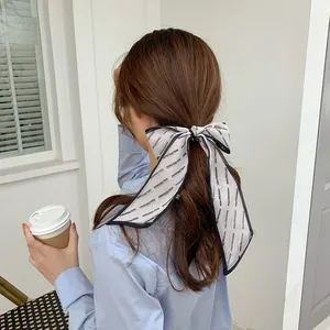 Detail of a beige mesh bow hair ribbon with black trim styled on a low ponytail
