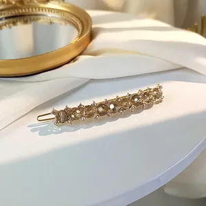 Detail of amber crystal hair clip with gold alloy base and white rhinestone accents