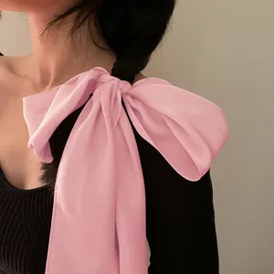 Détail d'un nœud en soie rose élégant avec de longs rubans fluides sur une queue de cheval