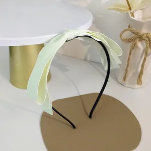 Détail du serre-tête à nœud vert clair sur un support décoratif dans un cadre minimaliste