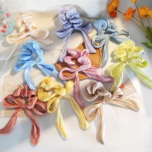 Vista piatta di elastici per capelli in raso colorato con fiocchi in varie tonalità pastello