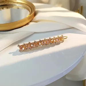 Macro detail of retro gold hair clip with amber crystal beads and tiny rhinestones