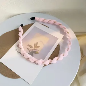 Dettaglio di un cerchietto in tessuto rosa chiaro intrecciato con filo dorato interno